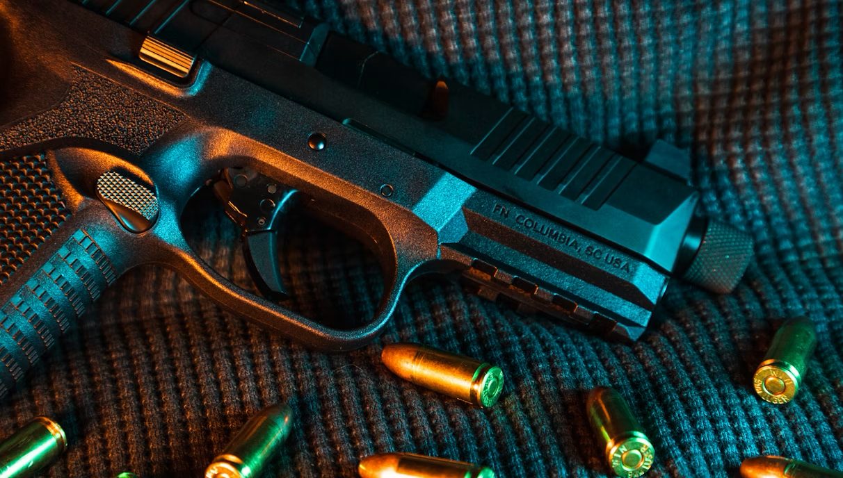 A handgun resting on fabric surrounded by scattered ammunition